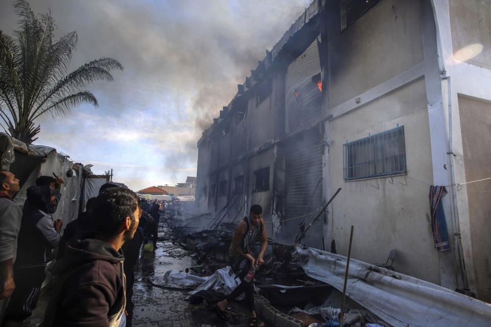 Palestinians try to extinguish a fire at a building of an UNRWA vocational training center which displaced people use as a shelter, after being targeted by Israeli tank shill in Khan Younis, southern Gaza Strip, Wednesday, Jan. 24, 2024. (AP Photo/Ramez Habboub)