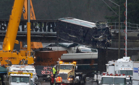A damaged Amtrak train car is lowered from an overpass at the scene of Monday's deadly train crash  - Credit: Elaine Thompson/AP