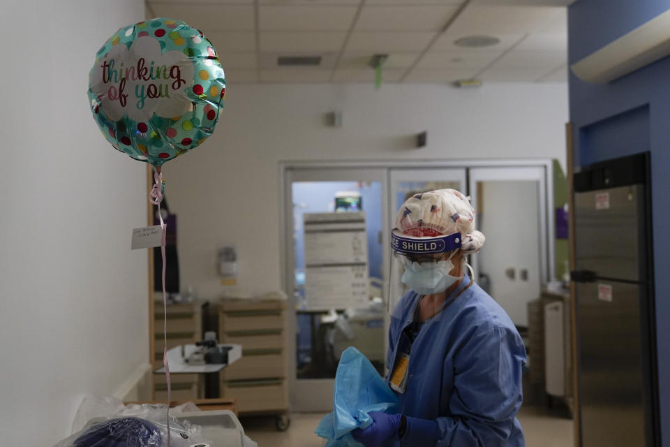Registered nurse Anita Grohmann puts on her PPE next to a balloon delivered to a patient in a COVID-19 unit at St. Joseph Hospital in Orange, Calif. Thursday, Jan. 7, 2021. The virus is surging in virtually every state. California is particularly hard hit, with skyrocketing deaths and infections threatening to force hospitals to ration care. (AP Photo/Jae C. Hong)
