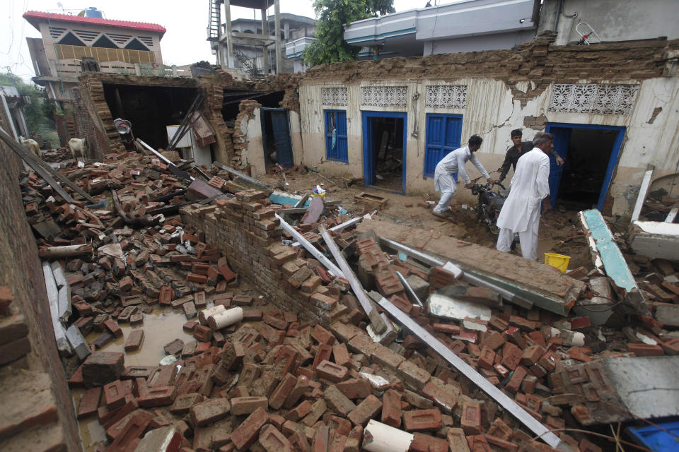 People recover belongings from the rubble of their damage house caused by a powerful earthquake at Sahang Kikri village near Mirpur, northeastern Pakistan, Wednesday, Sept. 25, 2019. Mourners were burying their dear ones in Pakistan-held Kashmir where a powerful earthquake struck a day before. (AP Photo/Anjum Naveed)
