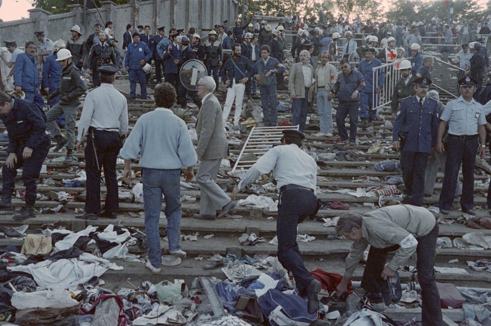 Rescuers and policemen search for victims on May 29, 1985 at the scene of riots in Heysel football stadium in Brussels after 39 people lost their lives in violent incidents, one hour before the European Champion Clubs final between Britain's Liverpool and Italy's Juventus of Turin. The tragedy occured when a wall collapsed in the stadium under the pressure of people and crushed Juventus fans as they tried to escape Liverpool supporters. (Photo by DOMINIQUE FAGET / AFP) (Photo by DOMINIQUE FAGET/AFP via Getty Images)