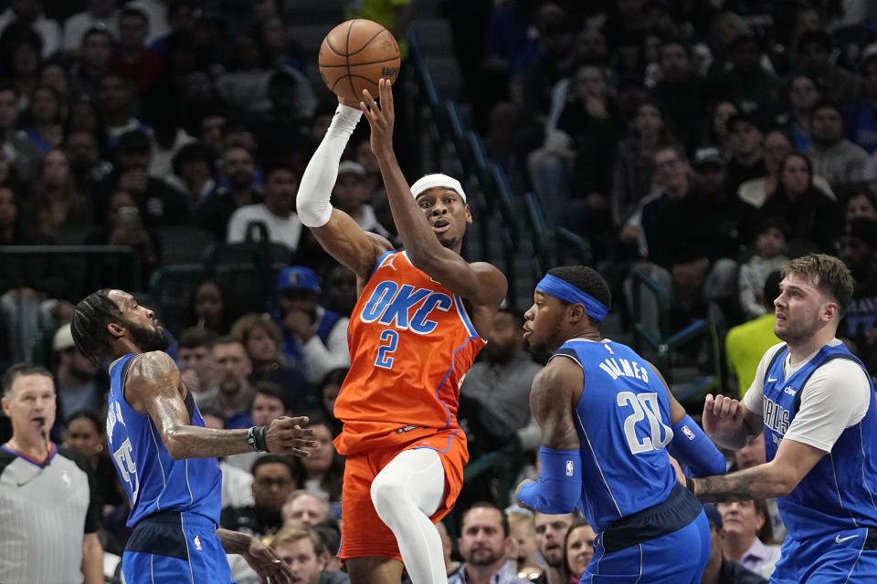 Oklahoma City Thunder guard Shai Gilgeous-Alexander (2) passes against Dallas Mavericks defenders Derrick Jones Jr. (55), Richaun Holmes (20) and Luka Doncic (77) during the first half of an NBA basketball game in Dallas, Saturday, Dec. 2, 2023. (AP Photo/LM Otero)