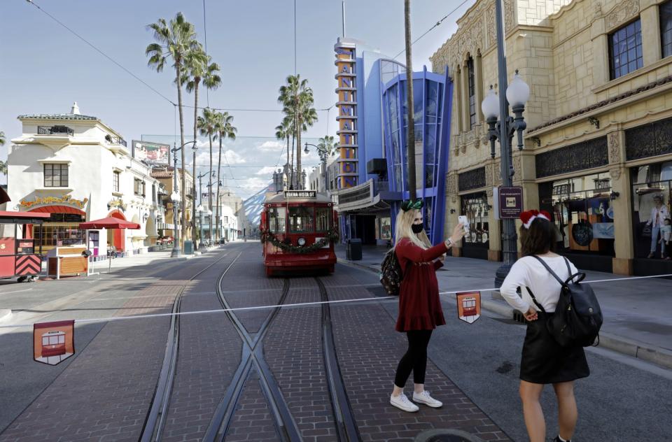 Two pedestrians and a bus on Buena Vista Street.