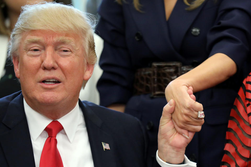 U.S. President Donald Trump holds first lady Melania Trump's hand as they attend an event to award the 2017 National Teacher of the Year at the Oval Office of the White House in Washington, DC. on April 26.