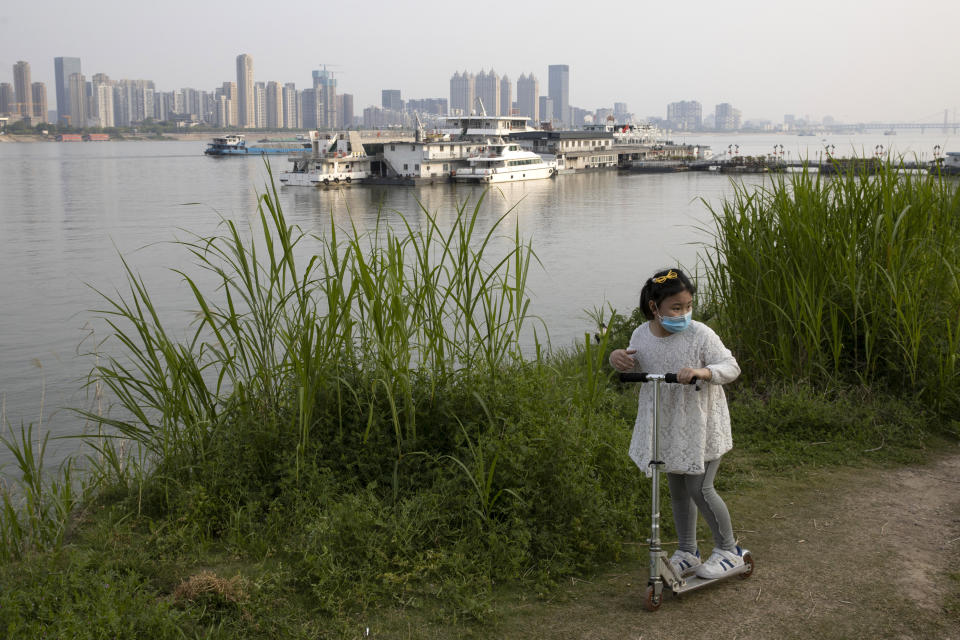 In this April 16, 2020, photo, a child wearing a mask against coronavirus rides her push bike along the banks of the Yangtze River in Wuhan in central China's Hubei province. Wuhan has been eclipsed by Shanghai, Hong Kong and other coastal cities since the ruling Communist Party set off a trade boom by launching market-style economic reforms in 1979. But for centuries before that, the city was one of the most important centers of an inland network of river trade that dominated China's economy and politics. (AP Photo/Ng Han Guan)