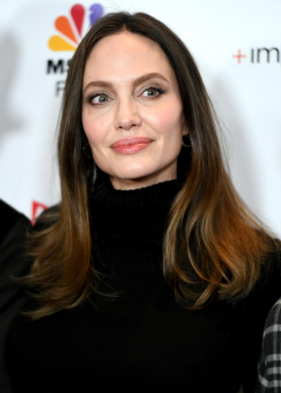 Angelina Jolie at an event, wearing a black turtleneck sweater