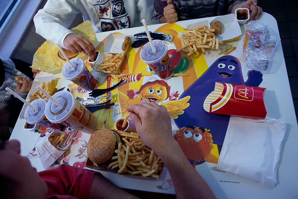 Children eating hamburgers, french fries, and chicken nuggets from McDonald's.