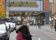 A woman wearing a face mask walks in Manchester, England, Monday, Oct. 19, 2020. Britain’s government says discussions about implementing stricter restrictions in Greater Manchester must be completed Monday because the public health threat caused by rising COVID-19 infections is serious and getting worse. (Peter Byrne/PA via AP)