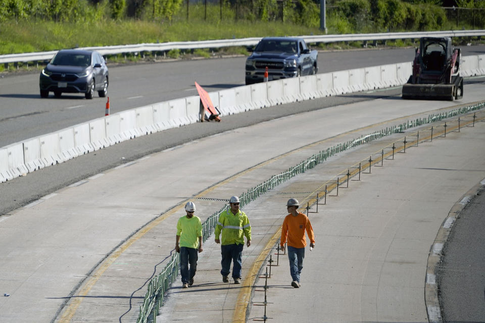 FILE - Traffic flows past workers in a construction zone along Interstate 55 in St. Louis, June 9, 2022. United States transportation officials announced $2.2 billion for local infrastructure projects on Thursday, Aug. 11, 2022, paving the way for new bicycle lanes, bridges, roads, railways and ports in scores of communities across the country. (AP Photo/Jeff Roberson, File)