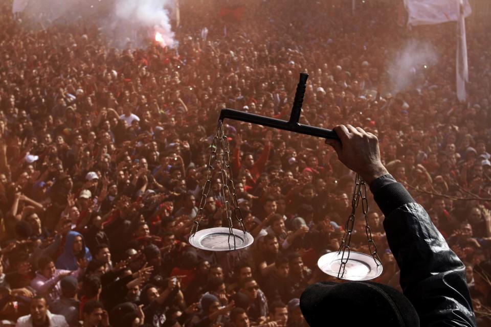 FILE - In this Saturday, Jan. 26, 2013 file photo, an Egyptian soccer fan of Al-Ahly club displays scales to fans celebrating a court verdict that returned 21 death penalties in last years soccer violence, inside the club premises in Cairo, Egypt. A verdict sentencing more than 520 people to death Monday, March 24, 2014 after a cursory mass trial has drawn new attention on Egypt’s judiciary, where many judges are strong backers of the military and sharp opponents of Islamists, operating amid a media frenzy calling for swift and harsh verdicts against the Muslim Brotherhood. (AP Photo/Ahmed Ramadan, File)