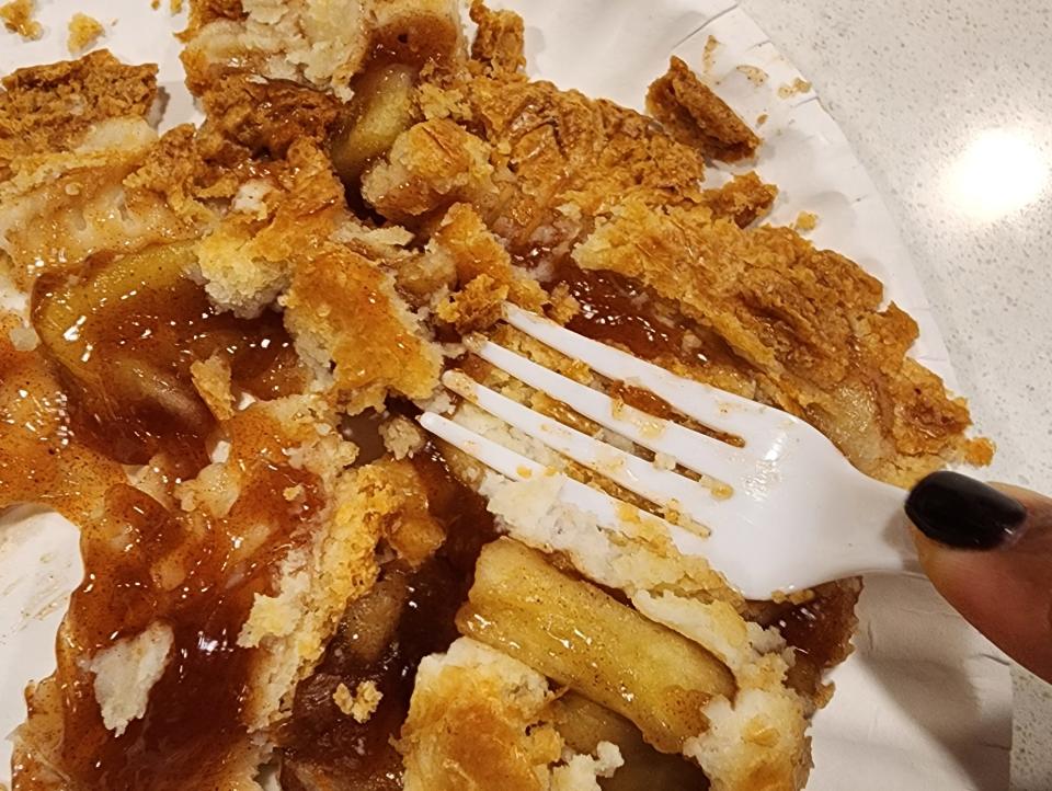 The writer flattening a piece of apple pie with a plastic fork