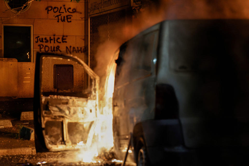 A car burns as slogans are seen on a wall which reads in French “Police kills, Justice for Nahel” during protests in Nanterre, on June 28, 2023.<span class="copyright">Geoffroy Van der Hasselt—AFP/Getty Images</span>