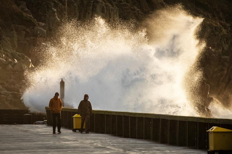 Bia zvedla obrovské vlny, které ponořily pobřežní města.  Lidé chodí po chodníku v Hammerhaven poblíž Sandvig na ostrově Bornholm v Baltském moři v Dánsku 22. prosince 2023 poté, co zemi zasáhla bouře Pia.