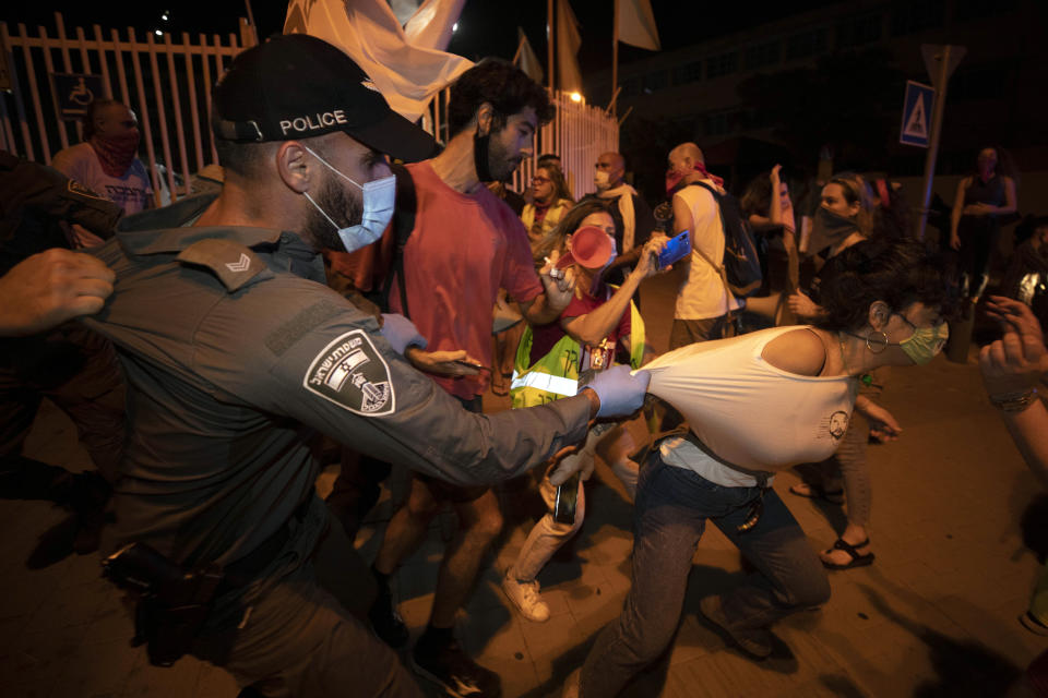 An Israeli police officer tries to stop an Israeli protester during a demonstration against lockdown measures that they believe are aimed at curbing protests against Prime Minister Benjamin Netanyahu, in n Tel Aviv, Israel, Thursday, Oct. 1, 2020. (AP Photo/Sebastian Scheiner)