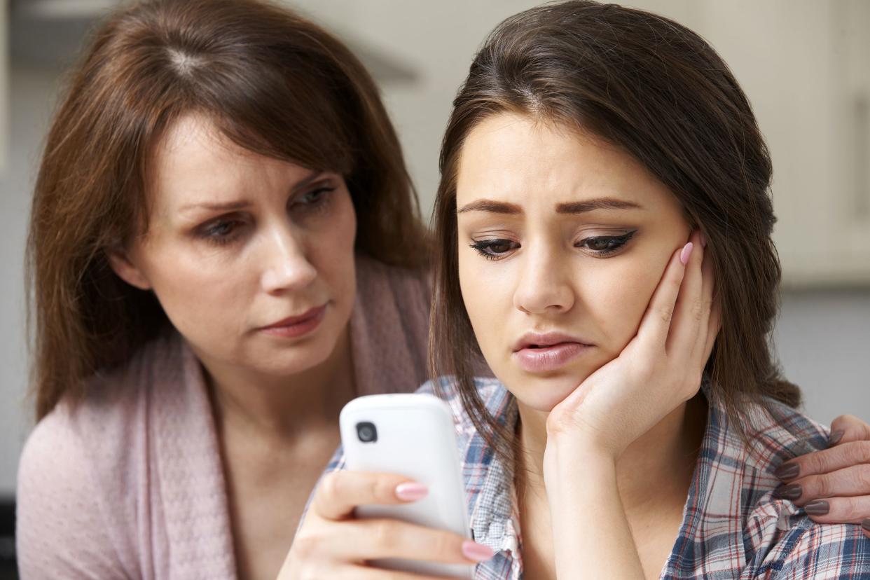 Mom consoling her depressed daughter on her phone