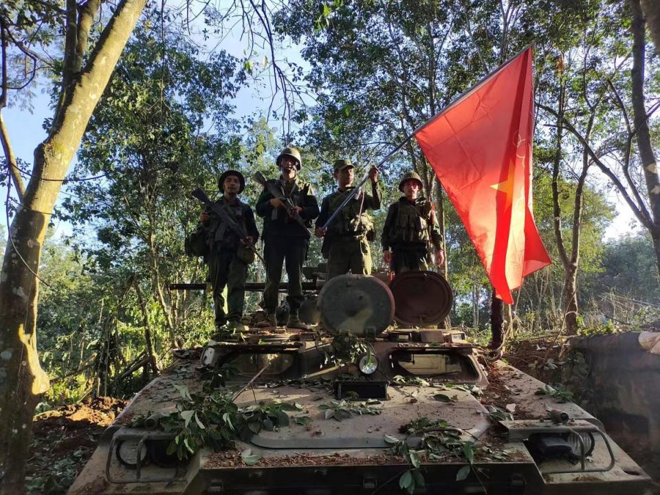 Members of the Myanmar National Democratic Alliance Army hold the group’s flag as they pose for a photograph on a captured army armored vehicle in Myanmar (AP)