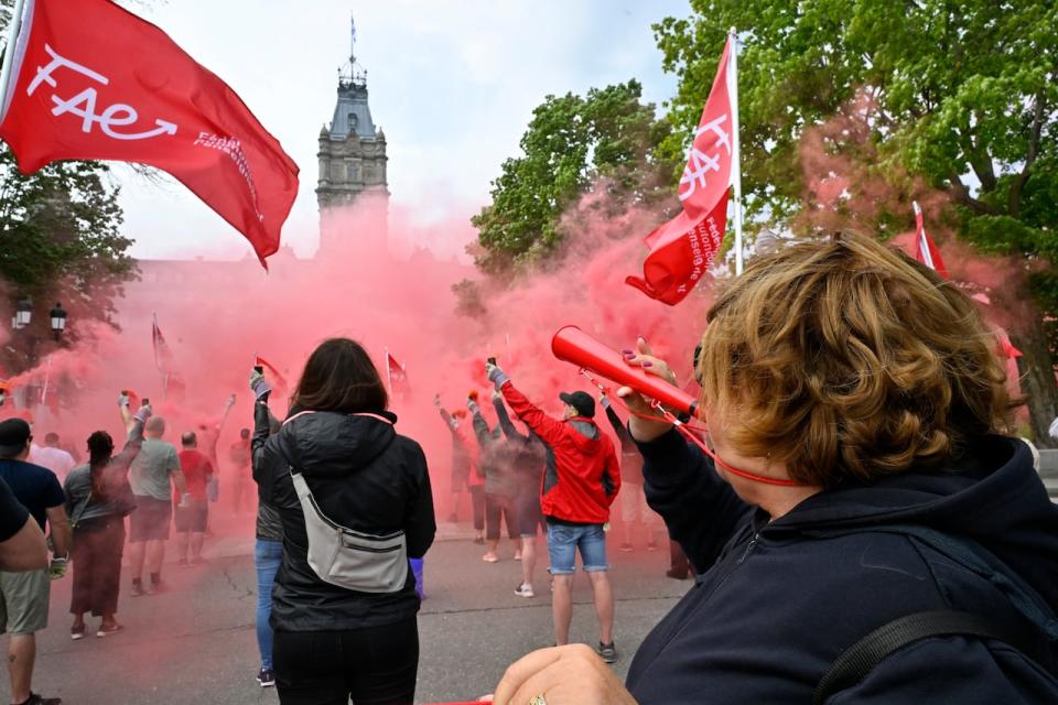 A teacher blows her horn as demonstrators create a smoke screen to protest Quebec's Bill 23 on education, Friday, June 2, 2023 at the legislature in Quebec City. THE CANADIAN PRESS/Jacques Boissinot