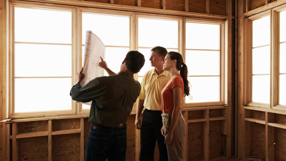 Husband and wife consulting with a architect inside a home under construction.