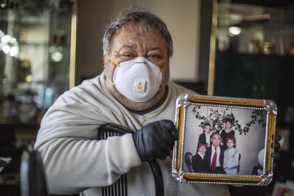 Michael Tokar holds a picture of his father, David Tokar, as he cleans out his apartment after he died from complications caused by coronavirus, in the Brooklyn borough of New York, Sunday, April 12, 2020. "He was born 92 years ago," said Tokar, reciting a collection of facts that form a portrait. "He collected stamps. He loved the racetrack. He adored his grandchildren." (AP Photo/David Goldman)