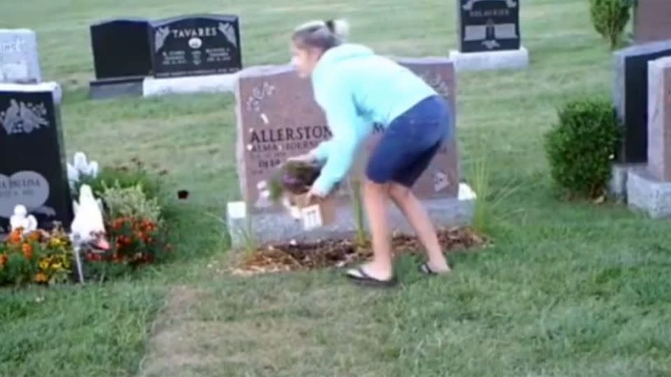A blonde woman can be seen with a small box in front of Alma's grave, ripping up the planted flowers from the ground. Photo: Supplied