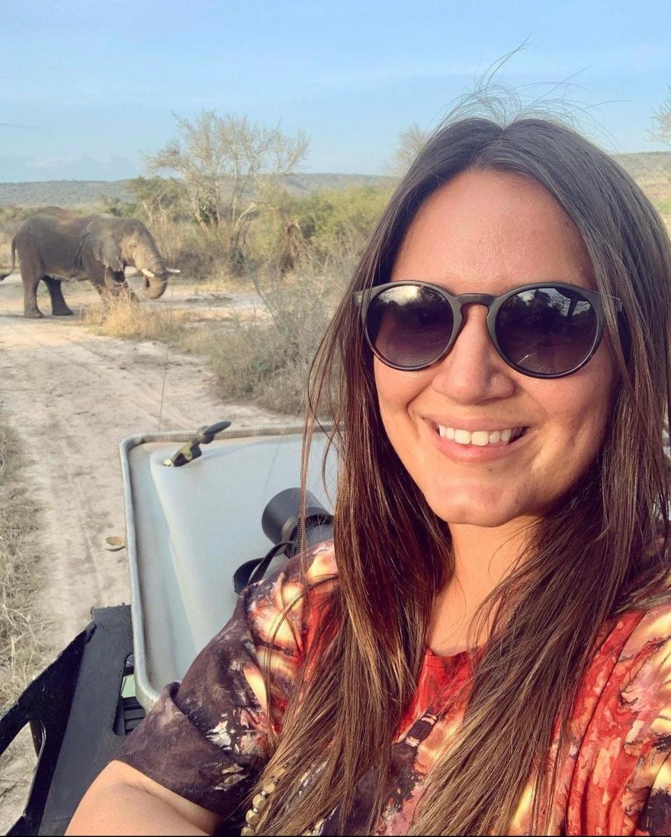 A woman on safari in front of an elephant.