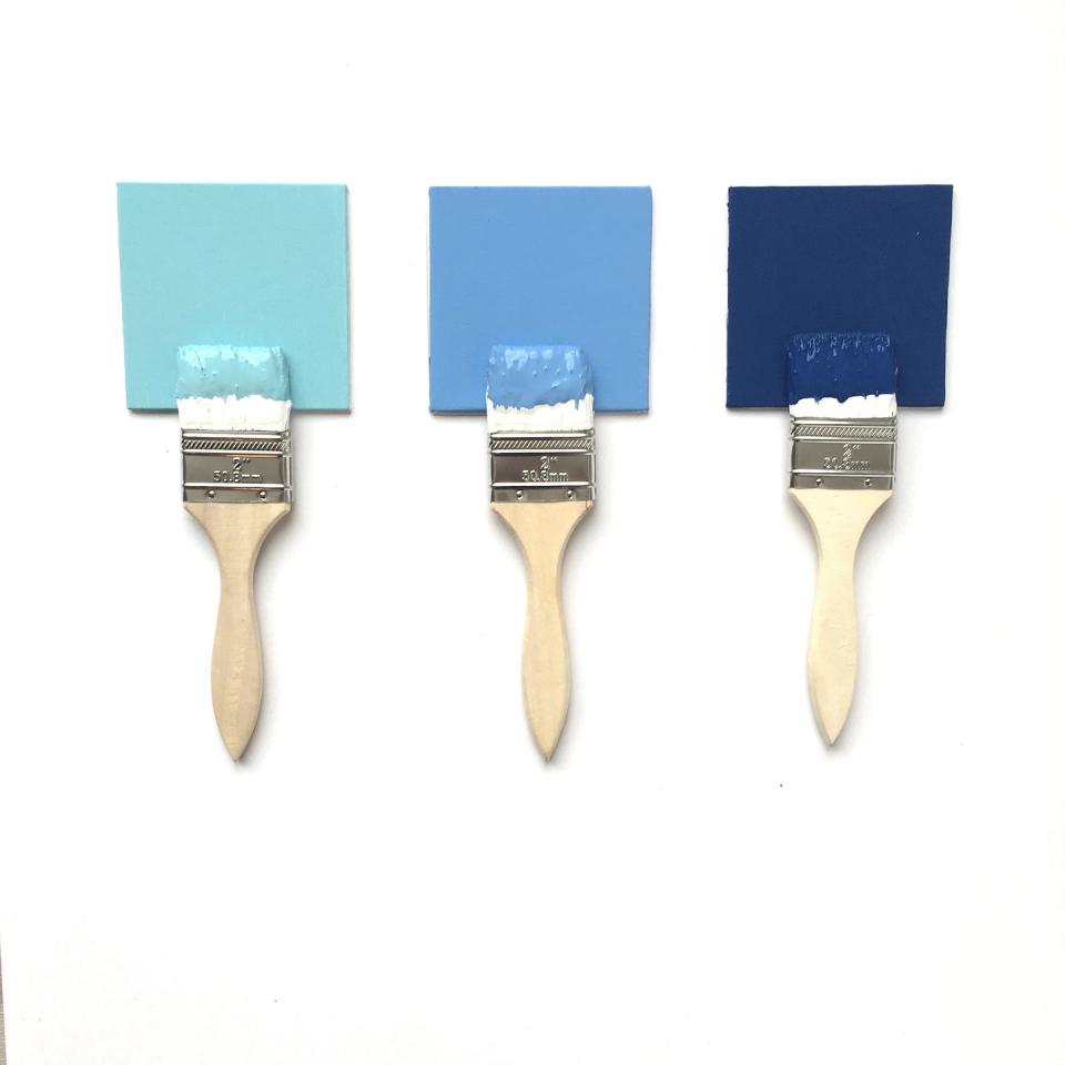 paint brushes dipped in shades of blue paint