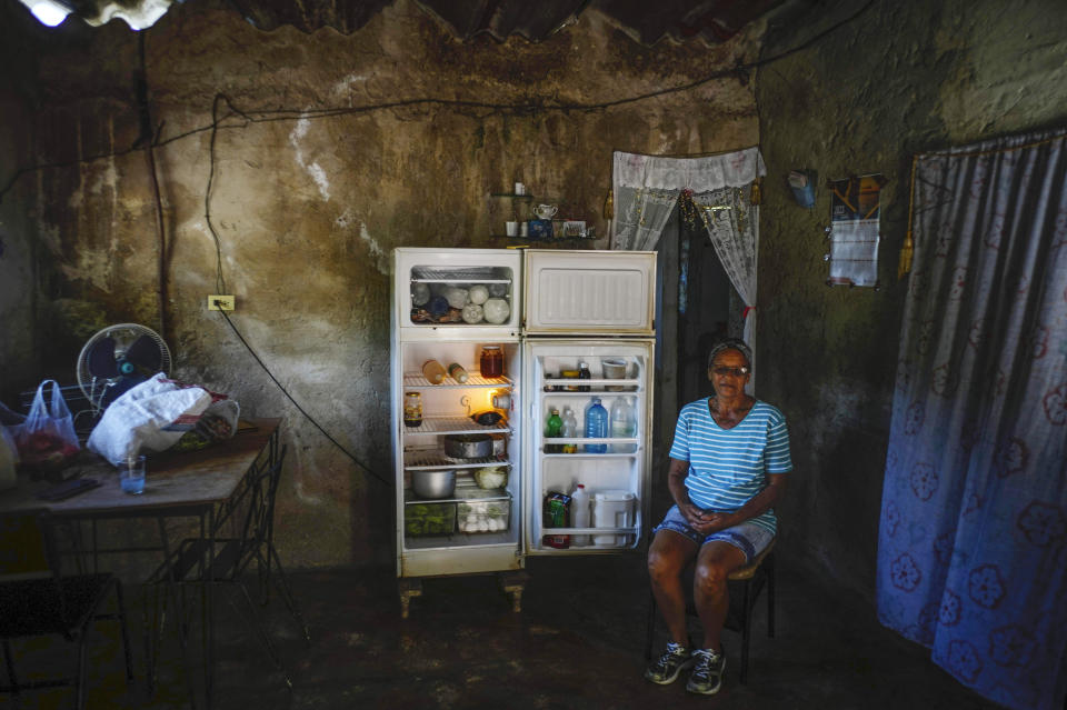 Rosa Lopez poses next to her refrigerator before preparing a meal for her grandchildren, amid a gas shortage in Mariel, Cuba, Thursday, May 18, 2023. It has been more than a month since any cooking gas has been delivered to Mariel, and the overall lack of gasoline for transportation has made the price of food rise. (AP Photo/Ramon Espinosa)