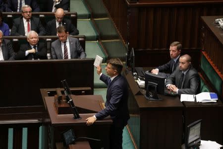 Leader of Modern party (.Nowoczesna) Ryszard Petru presents a copy of Timothy Snyder's "On Tyranny" as leader of Law and Justice (PiS) party Jaroslaw Kaczynski gestures during a debate before the voting on the bill that calls for an overhaul of the Supreme Court, at the parliament in Warsaw, Poland, July 20, 2017. Agencja Gazeta/Slawomir Kaminski/via REUTERS