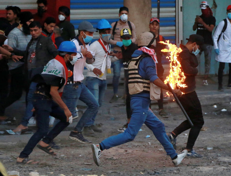 Demonstrators try to extinguish a protester who has caught fire, during clashes between Iraqi security forces and anti-Government protesters, in Baghdad, Iraq, Thursday, Nov. 21, 2019. Iraqi officials said several protesters were killed as heavy clashes erupt in central Baghdad. (AP Photo/Khalid Mohammed)