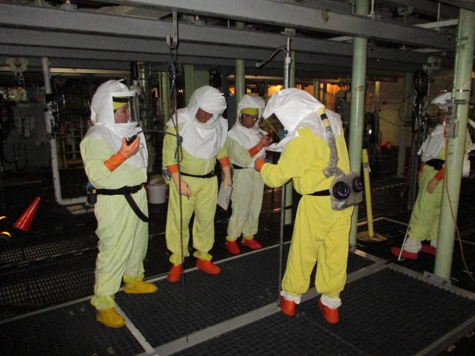 Workers stand on grating about the Hanford site K West Reactor basin to sort debris at the bottom of the 16-foot-deep pool. The work was needed to start pumping contaminated water from the basin.