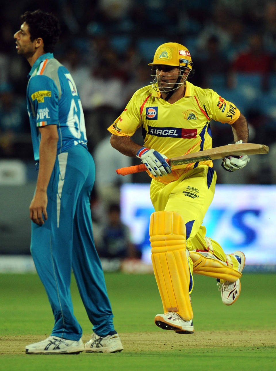 Pune Warriors India bowler Ashish Nehra (L) looks on as Chennai Super Kings batsman Mahendra Singh Dhoni takes a run during the IPL Twenty20 cricket match between Pune Warriors India and Chennai Super Kings at The Subrata Roy Sahara Stadium in Pune on April 14, 2012. RESTRICTED TO EDITORIAL USE. MOBILE USE WITHIN NEWS PACKAGE AFP PHOTO/Indranil MUKHERJEE (Photo credit should read INDRANIL MUKHERJEE/AFP/Getty Images)