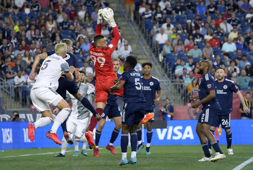 New England Revolution goalkeeper Djordje Petrovic (99) leaps above teammates to make a save next to Toronto FC's Lukas MacNaughton, left front, during the first half of an MLS soccer match Saturday, July 30, 2022, in Foxborough, Mass. (AP Photo/Mary Schwalm)