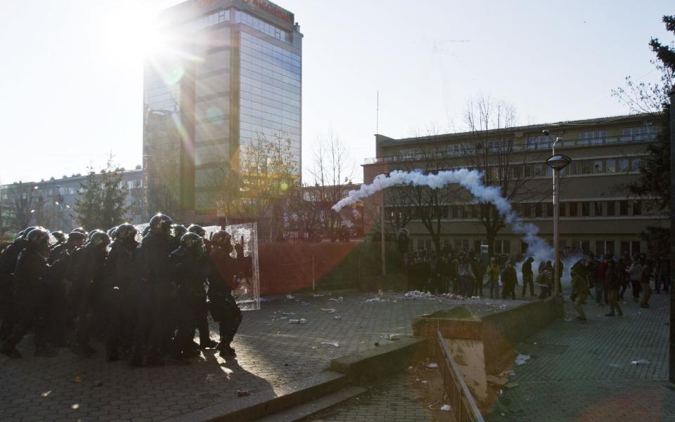 Protesters throws back a tear gas canister at Kosovo police officers preventing students from storming the building of the main public Pristina University on Friday, Feb. 7, 2014. Hundreds of protesters are trying to break through a police cordon and reach offices of the dean of the public university who protesters say faked his teaching credentials(AP Photo/Visar Kryeziu)