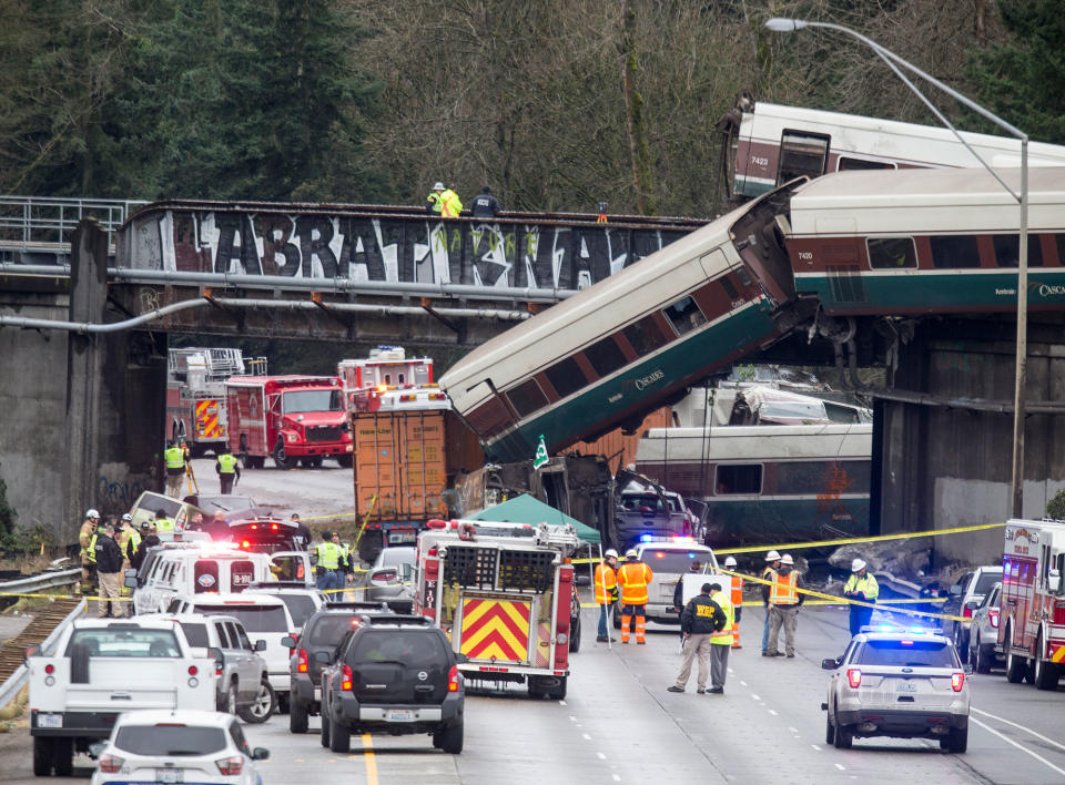 <p>DEC. 18, 2017 – Emergency crews work at the scene of a Amtrak train derailment in DuPont, Washington. At least three people were killed when a passenger train car plunged from the bridge. The derailment also closed southbound I-5. (Photo: Stephen Brashear/Getty Images) </p>