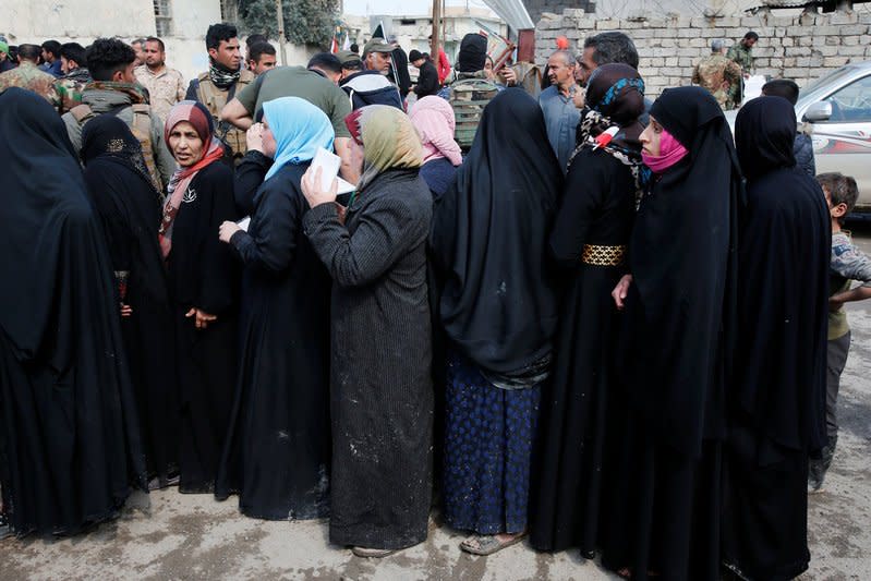 Civilians receive aid packages from Shi'ite humanitarian aid organisation in Al Ghizlane district as the battle against Islamic State's fighters continues in western city of Mosul, Iraq, March 20, 2017. REUTERS/Youssef Boudlal