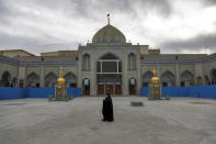 In this Saturday, March 7, 2020 photo, a woman with a mask walks in the yard of a Friday prayer mosque in Shahr-e-Ray, south of Tehran, Iran. The typically frenetic streets of Iran’s capital, Tehran, have fallen silent and empty due to the new coronavirus outbreak that’s gripped the Islamic Republic. (AP Photo/Ebrahim Noroozi)