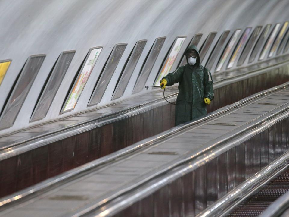 An employee wearing protective gear rides an escalator while spraying disinfectant to sanitize a metro station in Tbilisi, Georgia March 3, 2020. REUTERS:Irakli Gedenidze .JPG