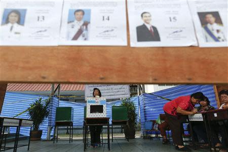 A voter signs documents before casting her ballot at a polling station in Bangkok during a vote to elect a new Senate March 30, 2014. REUTERS/Damir Sagolj