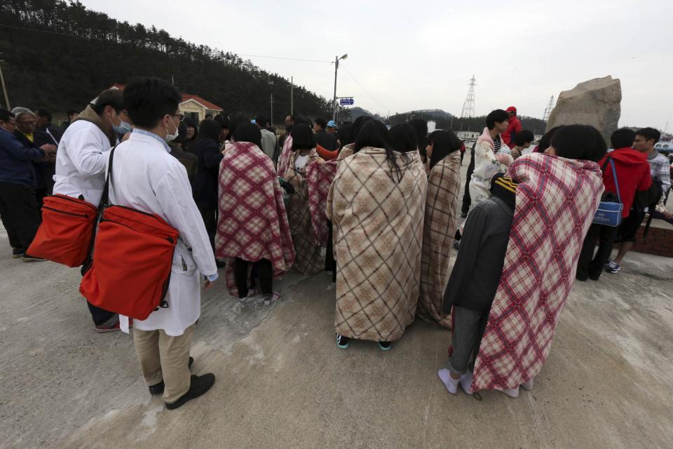 Rescued passengers wrapped in blankets, who were on a sinking ferry "Sewol" in the sea off Jindo, gather at a port in Seogeochado