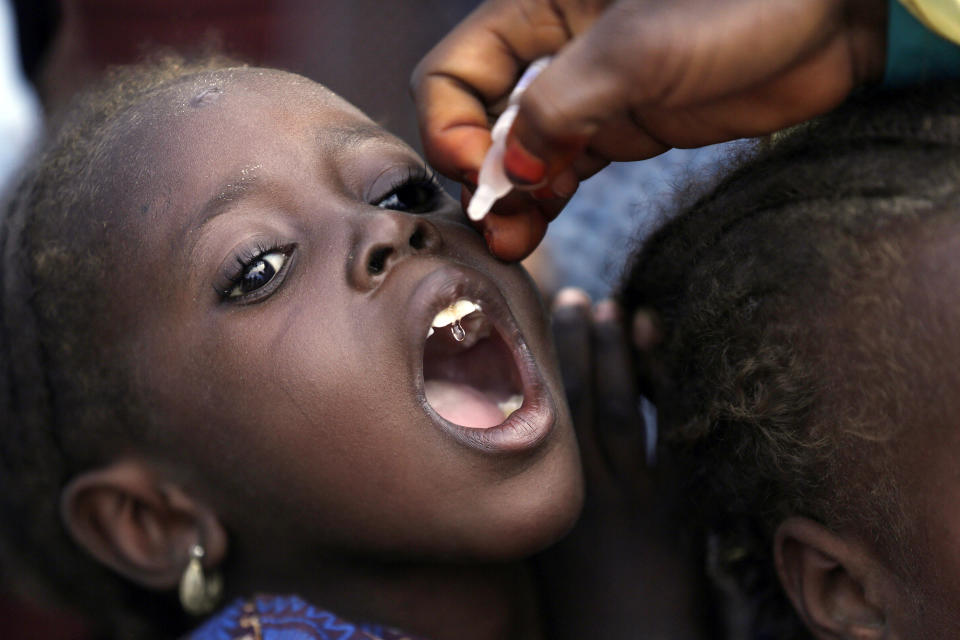 FILE - In this Sunday, Aug. 28, 2016 file photo, a health official administers a polio vaccine to a child at a camp for people displaced by Islamist Extremists, in Maiduguri, Nigeria. Health authorities on Tuesday, Aug. 25, 2020 are expected to declare the African continent free of the wild poliovirus after decades of effort, though cases of vaccine-derived polio are still sparking outbreaks of the paralyzing disease in more than a dozen countries. (AP Photo/Sunday Alamba, File)