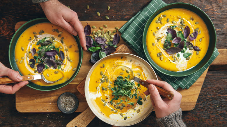 three creamy soups in bowls on a table