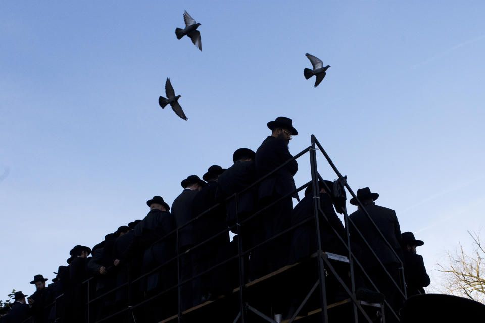 FILE - Pigeons fly above rabbis gathering for a group photo at the Chabad-Lubavitch World Headquarters, Sunday, Nov. 4, 2018, in New York. The synagogue in New York's Brooklyn borough is closely tied with Rabbi Menachem Mendel Schneerson's enduring influence in global Judaism and beyond in the three decades since his death, but it received unwanted attention in January 2024 with a brawl between some worshippers and police, part of a sequence of events that began with the discovery of a secretly dug tunnel. (AP Photo/Mark Lennihan, File)