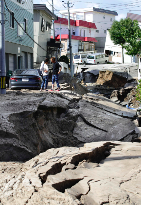 <em>Residents watch a road damaged by an earthquake in Sapporo, Hokkaido (AP)</em>