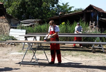 Welders are seen polishing iron beams in a courtyard in Cantavir, Serbia, July 6, 2017, after a grant received from the Hungarian government enabled the company to buy new machinery, boosting the amount of work he can take on. REUTERS/Bernadett Szabo