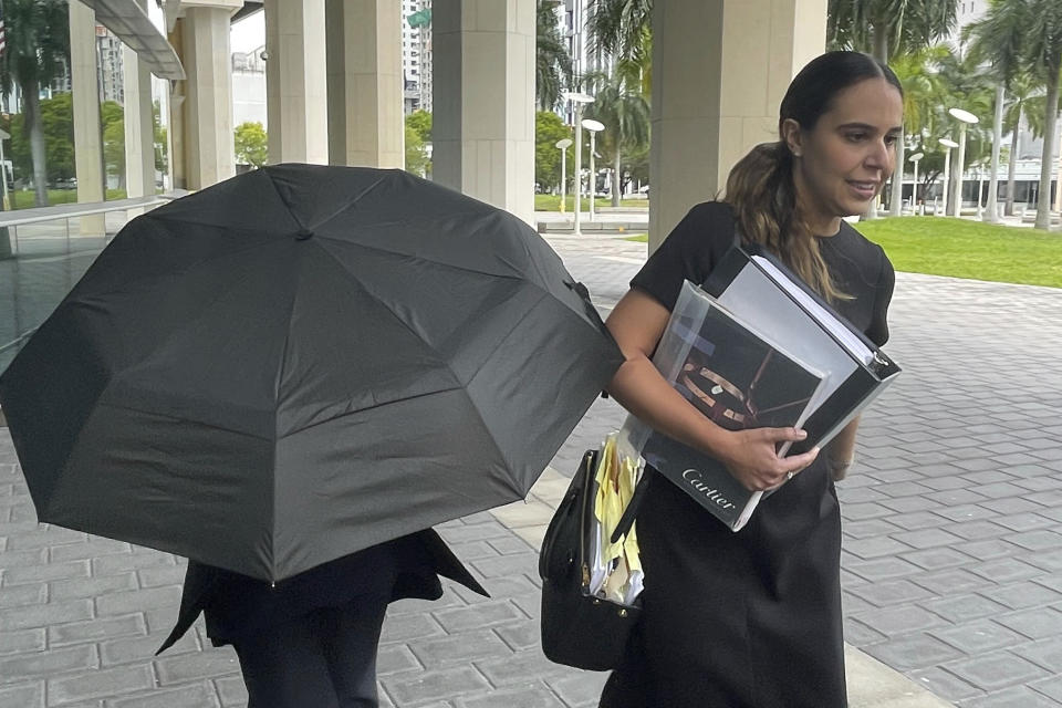 Celebrity handbag designer Nancy Gonzalez hides under an umbrella as she walks with her lawyer Andrea Lopez outside the federal courthouse Monday, April 22, 2024, in Miami. The Colombian designer, whose bags were purchased by celebrities like Britney Spears and the cast of the "Sex and the City" TV series, was sentenced to 18 months in federal prison on Monday for leading a smuggling ring that illegally imported into the U.S. crocodile handbags for sale at high end showrooms using couriers on commercial flights. (AP Photo/Josh Goodman)