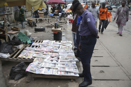 People read newspaper headlines at a vendor's stand along a road in Ikoyi district in Lagos July 18, 2014. REUTERS/Akintunde Akinleye