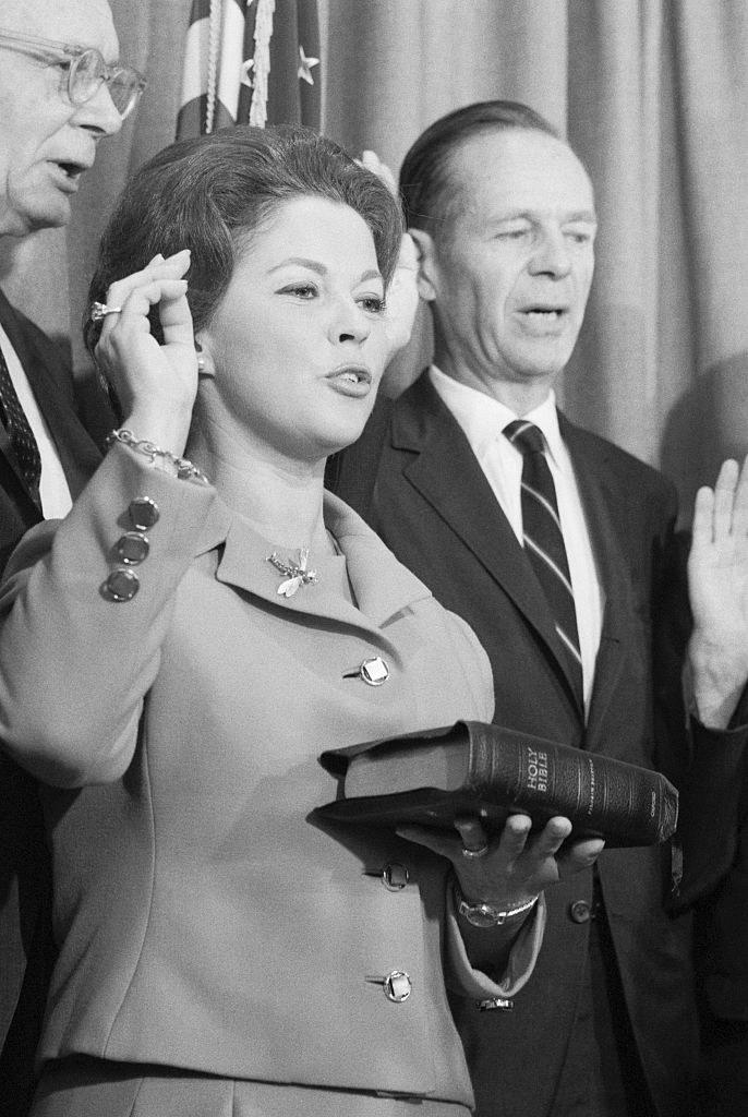 Adult Shirley holding a Bible and raising her other hand