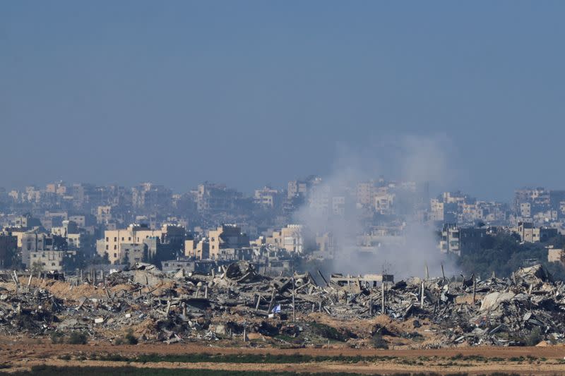 Una bandera israelí ondea junto a los escombros de edificios destruidos mientras se levanta humo en Gaza, en pleno conflicto entre Israel y el grupo islamista palestino Hamás, visto desde el sur de Israel