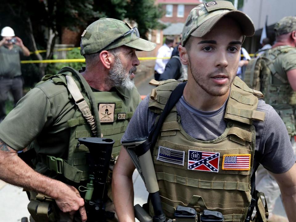 White nationalists, neo-Nazis and members of the 'alt-right' with body armor and combat weapons evacuate comrades who were pepper sprayed after the 'Unite the Right' rally was declared a unlawful gathering by Virginia State Police (Getty Images)