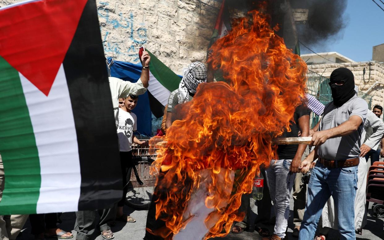 Palestinian protesters burn the flag of the United Arab Emirates (UAE) during a protest against the peace agreement to establish diplomatic ties between Israel and the United Arab Emirates, in the city of Yata, near Hebron, West Bank, - Shutterstock